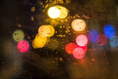 Ön plan üzerinde odaklanın. Araba camına yağmur damlaları. Arka plan trafik ve şehir ışıkları.