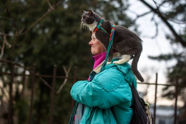 18.02.2019. Riga, Letonya. Omuz üzerinde onu kedi ile sokakta yürüyen kadın.
