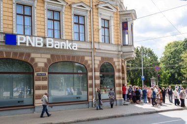 Riga, Letonya. 22 Ağustos 2019. İnsanlar, feshedilmiş Pnb Bank'ın (eski adıyla Norvik Bank) tazminat ödemelerini beklemek için arka arkaya duruyorlar. Pnb Bank, Avrupa Merkez Bankası'nın (Ecb) anonsu sonrasında kapandı.
