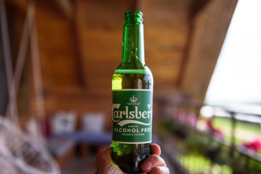 Lubana, Letonya. 1 Ağustos 2019. Bir adam elinde bir şişe Carlsberg Alcochol Bedava Organik Bira.