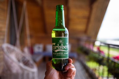 Lubana, Letonya. 1 Ağustos 2019. Bir adam elinde bir şişe Carlsberg Alcochol Bedava Organik Bira.