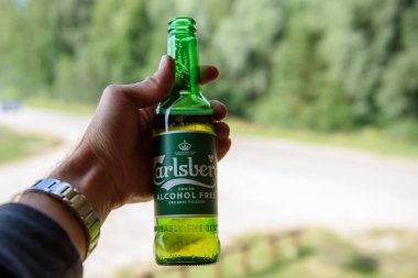 Lubana, Letonya. 1 Ağustos 2019. Bir adam elinde bir şişe Carlsberg Alcochol Bedava Organik Bira.