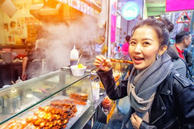 Çinli Asyalı Genç kadın modeli yemek Izgara ahtapot Hong Kong Caddesi üzerinde