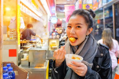 Çinli Asyalı Genç kadın modeli sokakta Hong Kong Çin buharda pişmiş hamur tatlısı yemek