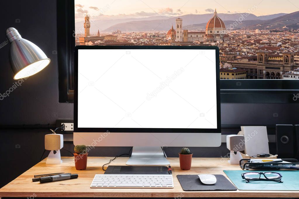 Graphic designer's workspace with a pen tablet, a computer and white backgroud for text with beautiful cityscape florence view from the window