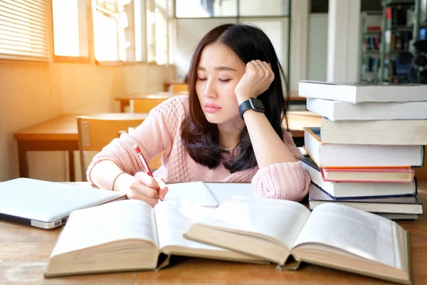 Young woman studying in a library and thinking of something — Stock Photo, Image