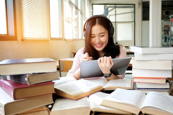 Young woman in a good mood listening to music  while using table — Stock Photo, Image