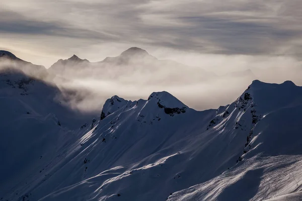 Montañas levantándose de las nubes antes del atardecer —  Fotos de Stock