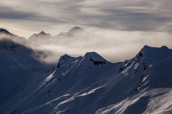 Berge, die sich vor Sonnenuntergang aus den Wolken erheben — Stockfoto