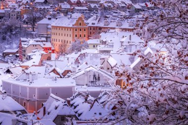 Cesky Krumlov 'un kış manzarası, kalenin altında karla kaplı çatıları olan resimli evler. Dar sokaklar ve Vltava nehri. Avrupa 'da seyahat ve tatil. Noel zamanı. UNESCO Dünya Mirası. Çek Cumhuriyeti