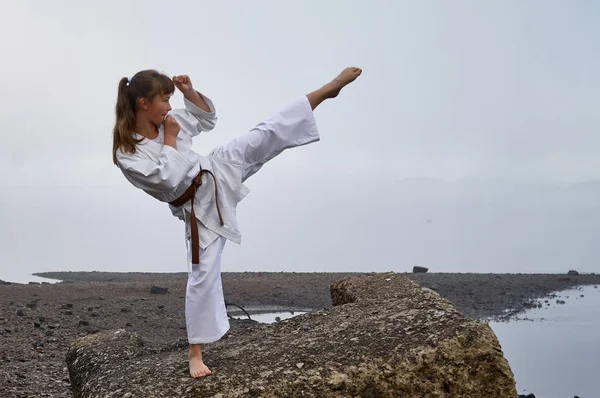 川海岸に日本の武道空手の練習着物姿の若い女性 霧深い早朝 ロイヤリティフリーのストック画像