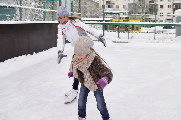 Gelukkig moeder en dochter schaatsen op een outdoor ijsbaan — Stockfoto