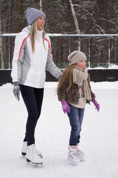 Gelukkig moeder en dochter schaatsen op een outdoor ijsbaan — Stockfoto