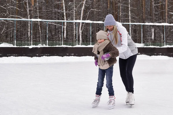 Gelukkig moeder en dochter schaatsen op een outdoor ijsbaan — Stockfoto