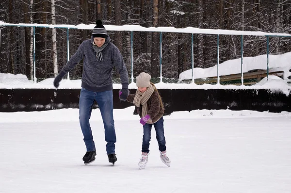 Vader en dochter schaatsen op de ijsbaan onder de blote hemel op een overwinning — Stockfoto