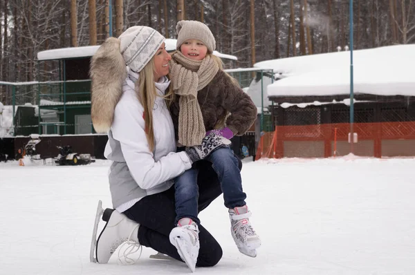 Happy mother and daughter skating on a outdoor skating rink