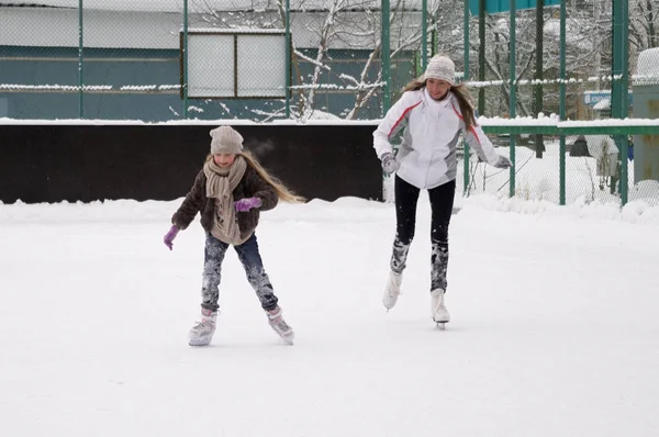 Gelukkig moeder en dochter schaatsen op een outdoor ijsbaan — Stockfoto