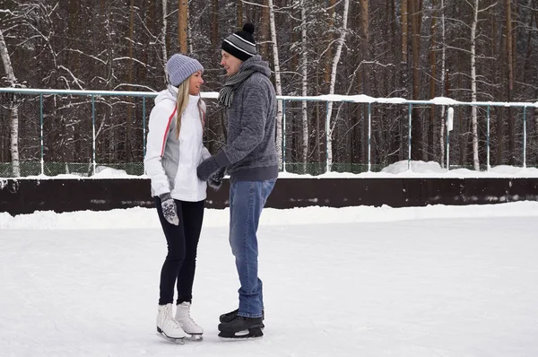 Genç çift halka açık bir buz pateni pistinde paten kayıyor. — Stok fotoğraf