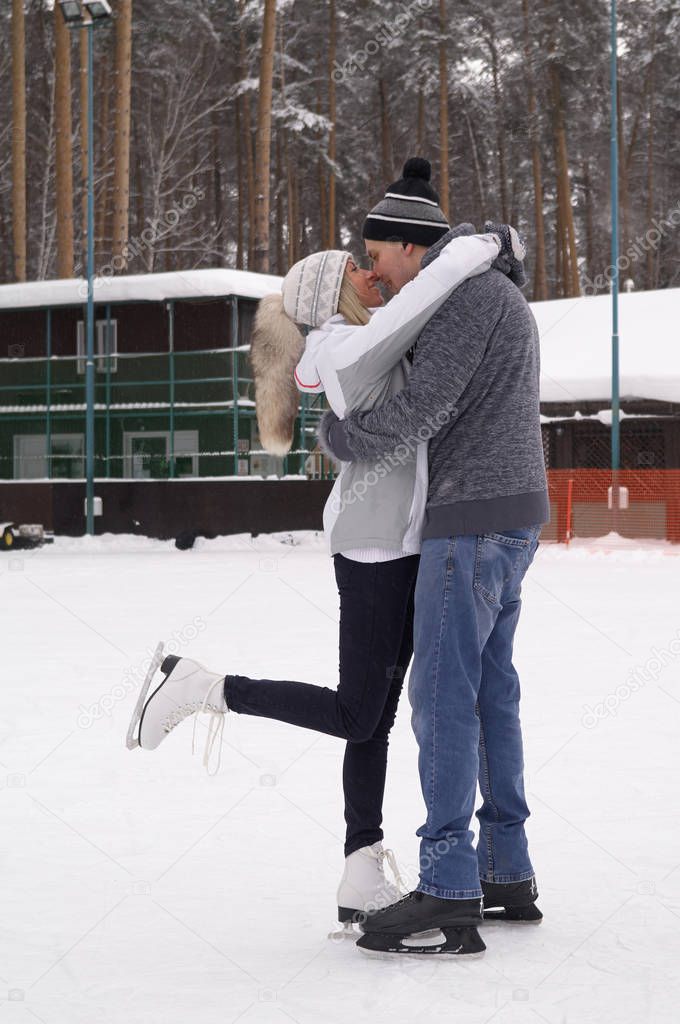 Young couple skating at a public ice skating rink outdoors in th