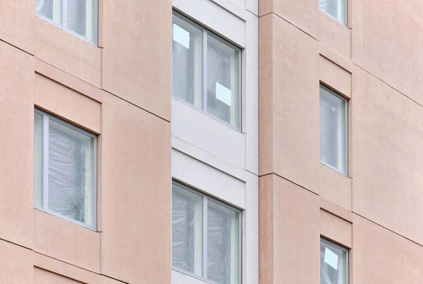 The modern pink facade of the apartment building in Finland. The modern nordic architecture. The building is under construction.