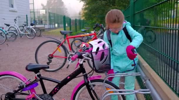 那女孩正试图在学校的自行车停放处把自行车挂上 — 图库视频影像