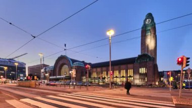 Helsinki, Finlandiya - 19 Eylül 2020: Helsinki Merkez Tren İstasyonu. Tren istasyonu tramvayı duruyor. İnsanlar caddeyi yürüyerek geçiyor. Gece şehir manzarası.