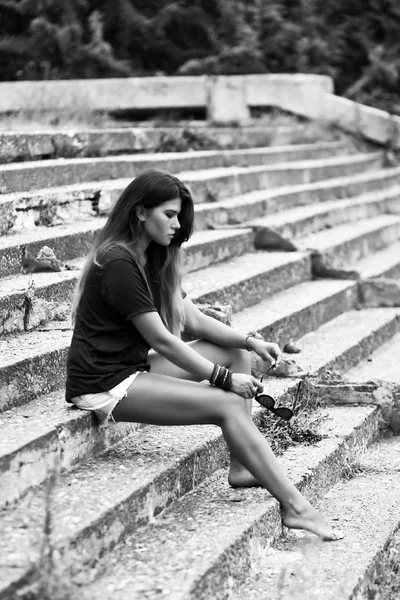 穿着短裤和衬衫的年轻美丽女孩穿着长长的腿坐在旧楼梯上 — 图库照片