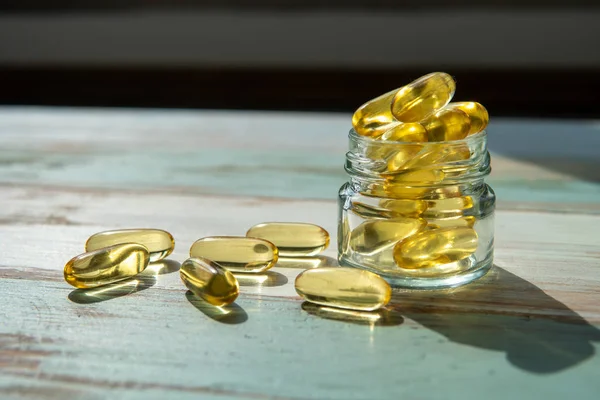 Fiskoljekapslar i glas flaska på träbord, Healthcare Co — Stockfoto