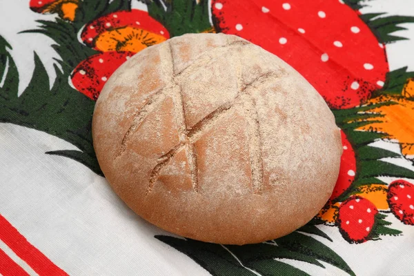 A loaf of round bread with a pattern on a bright tablecloth