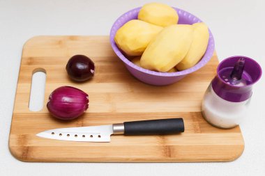 patates, soğan, tuz ve Doğrama Kurulu yan görünüm karşı açık mutfak masasının üzerinde bir mutfak bıçağı
