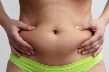 iki kadın eller kat fazla karın yağ tutun. gri bir arka plan üzerinde görünüm ön