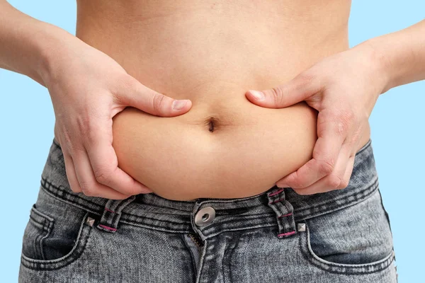 Dos Manos Mujer Sosteniendo Exceso Grasa Estómago Sobre Fondo Azul — Foto de Stock