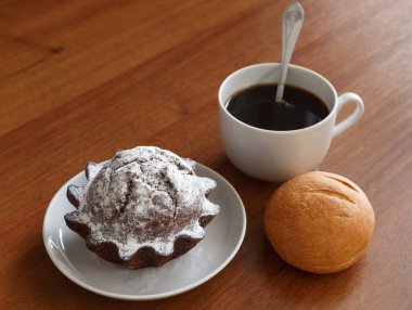 kahve kek küçük tabakta kupa, bun ve çikolata. Kahverengi ahşap arka plan üzerinde.