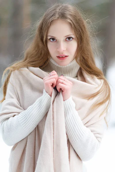 白のプルオーバーと冬の森の背景に大きなピンクのスカーフで美しい少女の垂直の肖像 — ストック写真