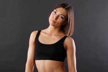 Yatay stüdyo varoluş portre güzel bir kızın mükemmel fiziksel şekli, spor giyim, tek tip koyu arka plan