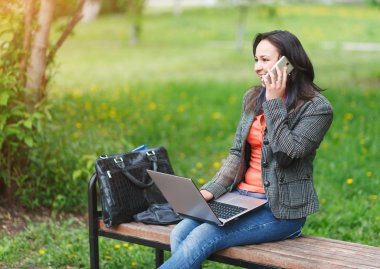 Dizüstü bilgisayarda çalışan ve Evet Genç Çevirmen kız Park, bankta oturuyor