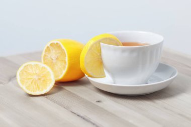 bir daire ahşap bir yüzeyi üzerinde beyaz bir bardak limonlu çay