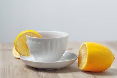 bir daire ahşap bir yüzeyi üzerinde beyaz bir bardak limonlu çay