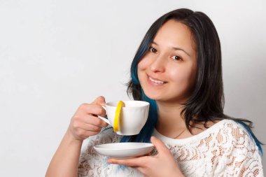 Bir kız bir limonlu çay içiyor. Tatlı bir içki. Nötr arka plan. Önden görünüm. Yakın çekim.