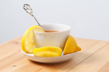 bir daire ahşap bir yüzeyi üzerinde beyaz bir bardak limonlu çay