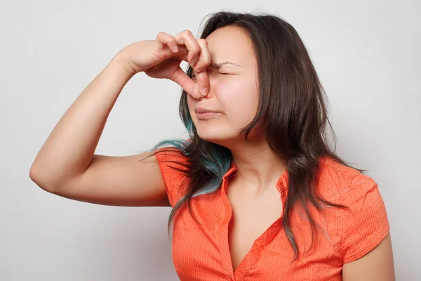 the girl wrinkles and closes her nose with two fingers from the unpleasant smell