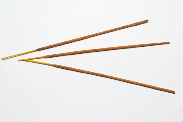 three Indian incense sticks on a solid light background