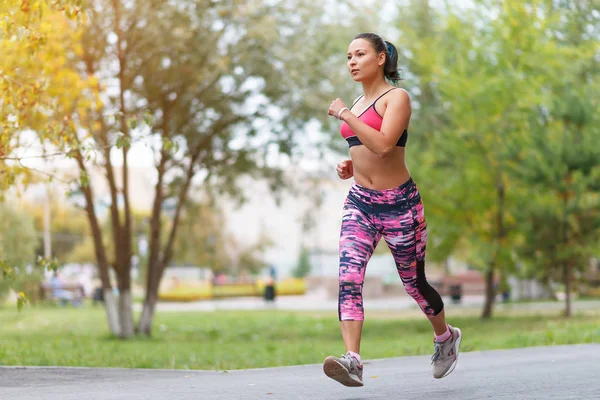 Young lady running. Woman runner running through the spring park road. Workout in a Park. Beautiful fit Girl. Fitness model outdoors. Weight Loss