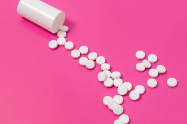 Daire uyuşturucu ya da pembe bir arka plan üzerinde beyaz plastik ilaç şişesi dışarı dökülmesini tablet hap