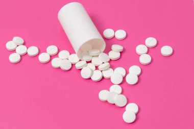 Daire uyuşturucu ya da pembe bir arka plan üzerinde beyaz plastik ilaç şişesi dışarı dökülmesini tablet hap