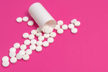 Daire uyuşturucu ya da pembe bir arka plan üzerinde beyaz plastik ilaç şişesi dışarı dökülmesini tablet hap