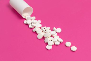 Daire uyuşturucu ya da pembe bir arka plan üzerinde beyaz plastik ilaç şişesi dışarı dökülmesini tablet hap