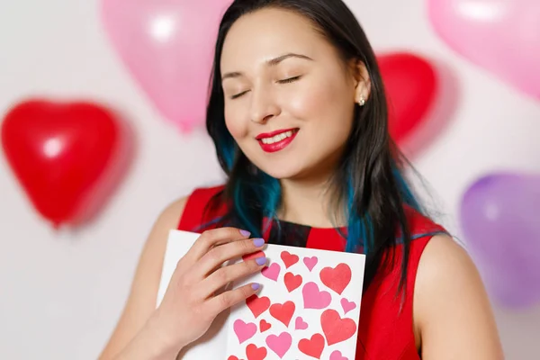 A beautiful young woman takes a card with hearts with a Declaration of love. Valentine's day — Stock Photo, Image