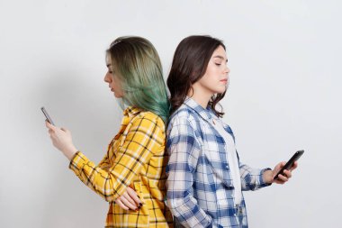 Modern teknolojiler ve internet bağımlılığı kavramı. Arka arkaya ve aramıyorum, online mesajlaşma konuşan Elektronik Gadget'ları, absorbe duran iki genç kadının.