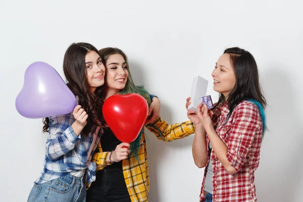 a young happy girl takes a holiday gift from her friends. On a neutral gray background